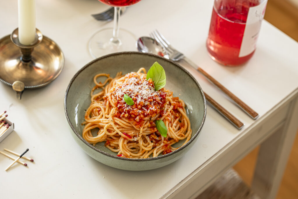 Teller mit Spaghetti und Linsen-Bolognese, Parmesan und Basilikum.