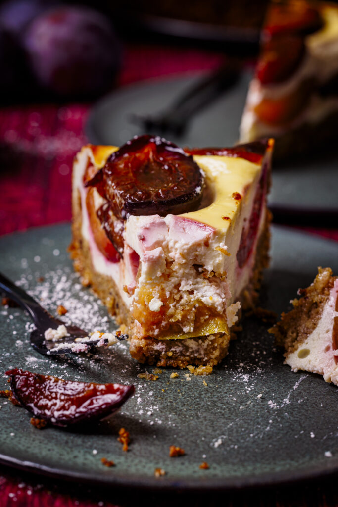 Mit Gabel angestochenes Stück Topfen-Zwetschgenkuchen auf Teller (Close-up).