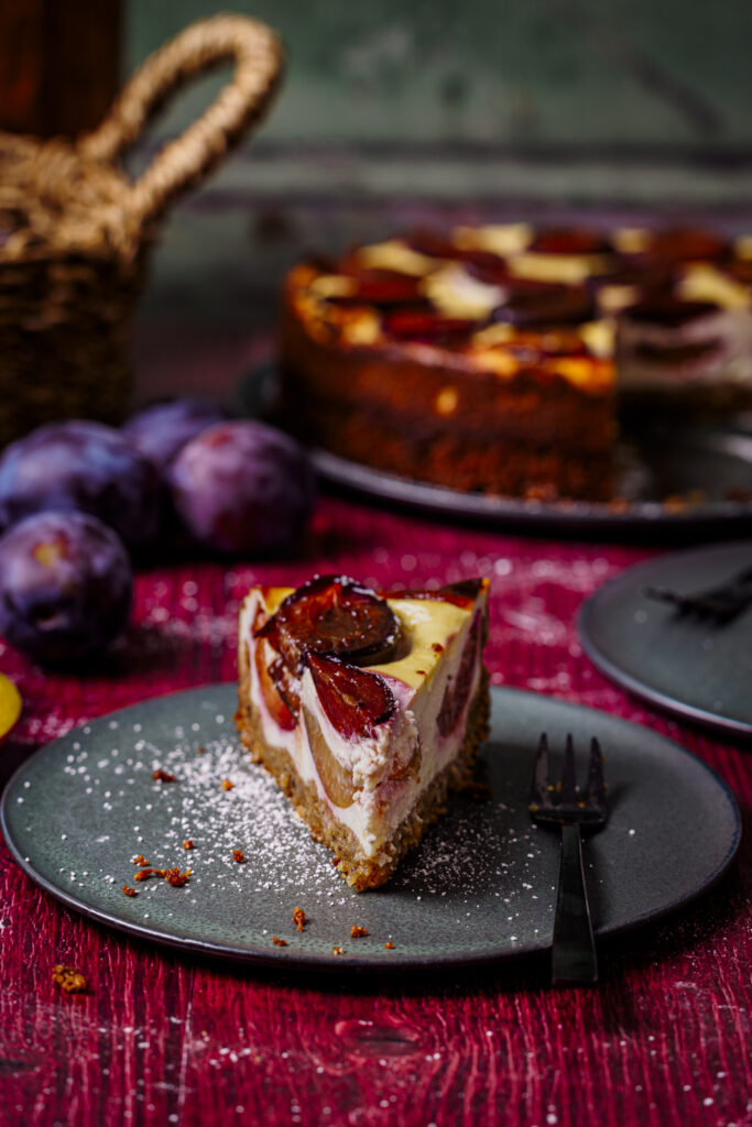 Ein Stück Zwetschkenkuchen mit Nüssen und Topfen auf Kuchenteller (Schrägsicht).